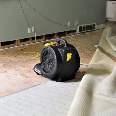 High-speed air blower drying a water-damaged floor area inside a Melbourne home
