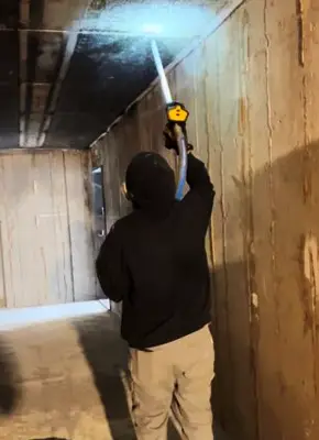 Technician using dry ice blasting to remove soot from a fire-damaged wall