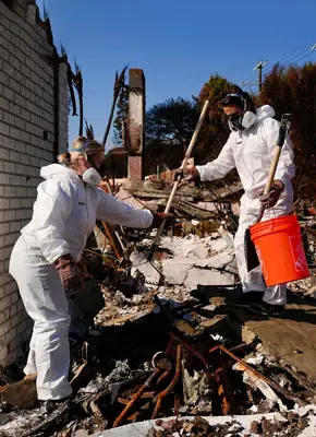 Workers clearing fire debris and waste from a damaged building site