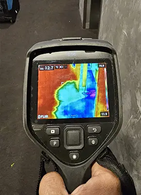 Technician using a moisture meter to assess dampness in wet carpet flooring at a Melbourne property