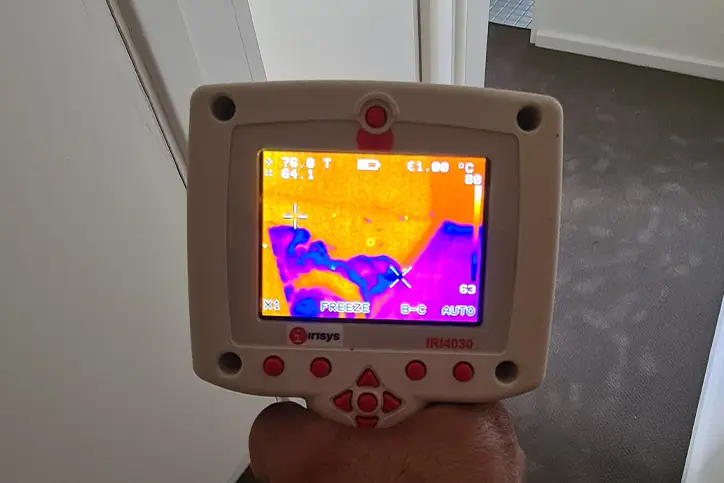 Technician recording moisture levels with monitoring equipment for an insurance report in a Melbourne property