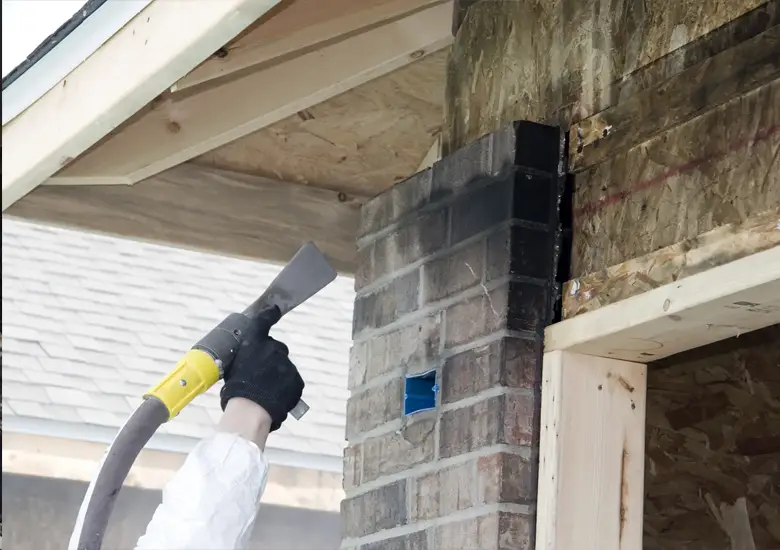 Technician cleaning black soot and smoke residue from a fire-damaged wall
