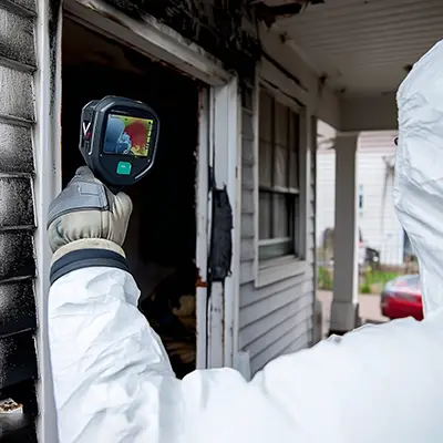 Technician using thermal scanner to detect hidden damage in a fire-affected Melbourne property