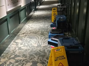 Professional-grade drying equipment used to restore a wet carpet in a hotel corridor after water damage in Melbourne.