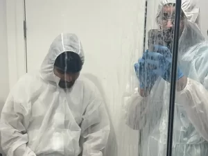 Technician in hazard uniform documenting a wet mirror with visible water stains during inspection in a Melbourne property.