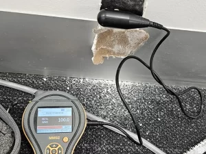 Moisture meter showing high readings on a wet concrete wall in a Melbourne property during inspection.