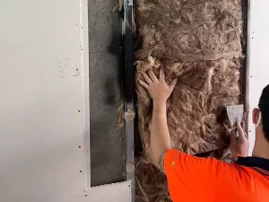 Technician removing wet and mould affected glasswool insulation from a Melbourne property during restoration.