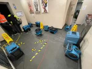 Restoration equipment deployed in a flooded lobby area to remove water and dry surfaces after a flood in a Melbourne building.